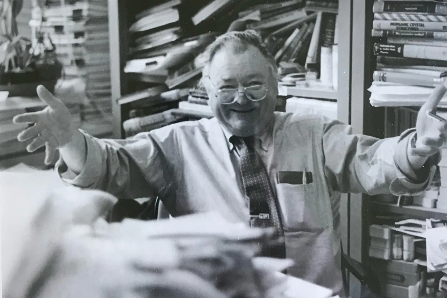 Photo du professeur émérite Bernie Wuensch assis dans son bureau, avec des livres et des piles de papier tout autour de lui.